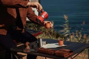 A man pouring coffee outdoors, representing calm presence, routine, and mindful moments of self-care and reflection.