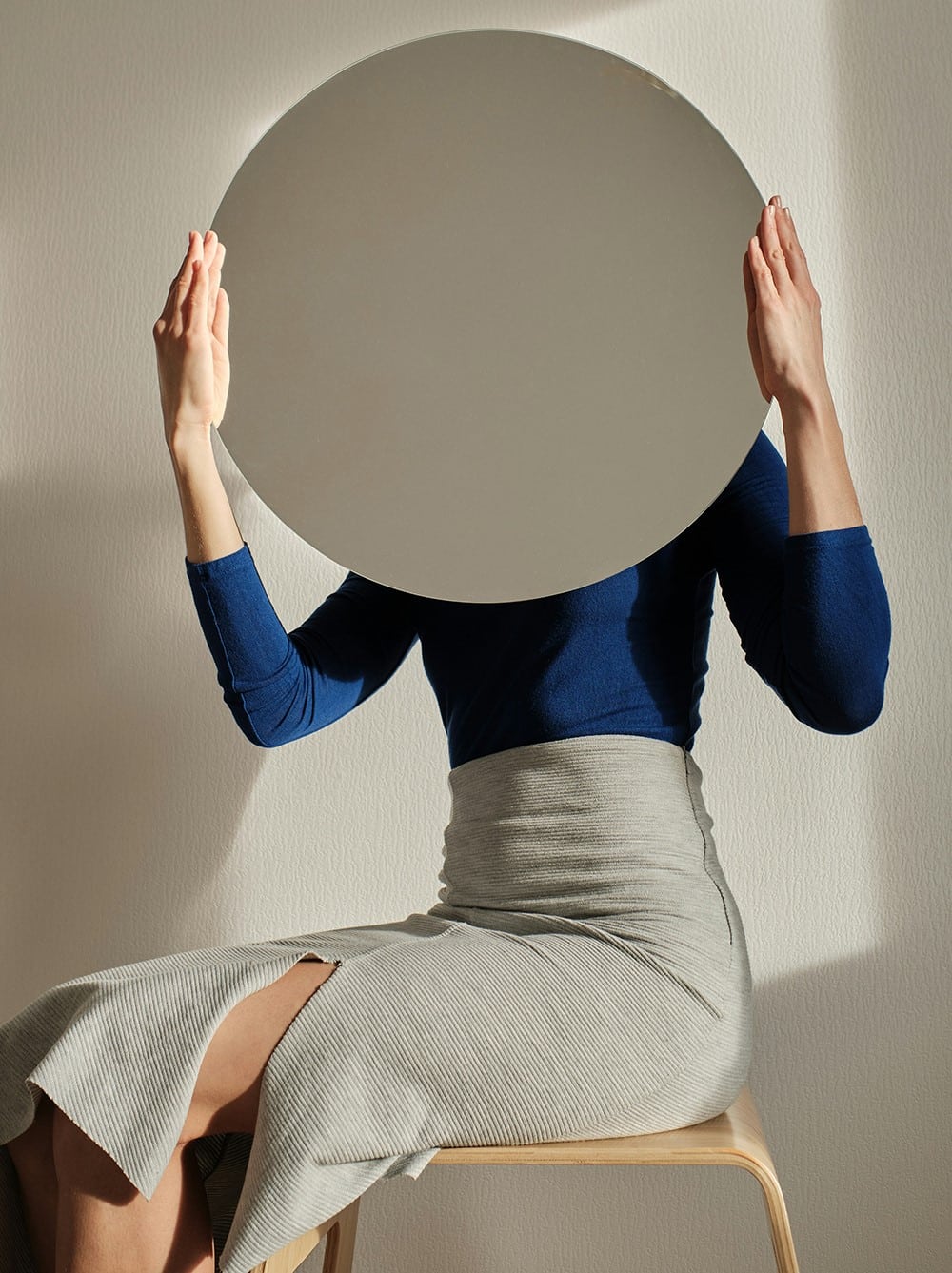 A person seated on a wooden stool
