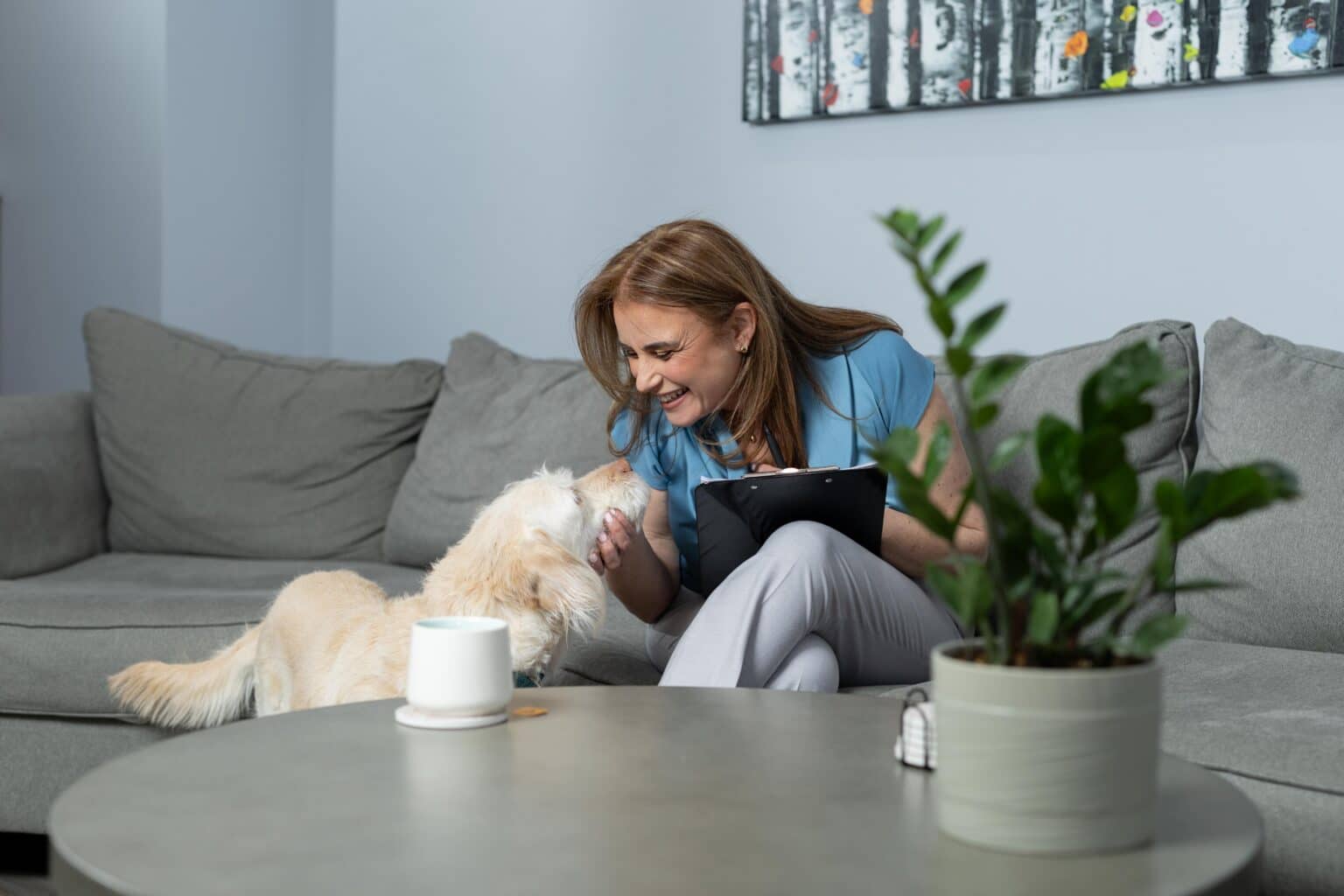 Nellie Harari, a CBT and ACT-trained professional, smiles while playing with her dog, conveying warmth and approachability.