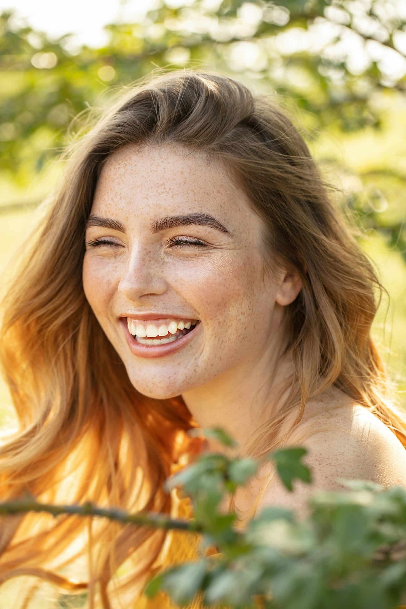 A woman smiling warmly, expressing confidence, ease, and a sense of emotional well-being and self-acceptance.