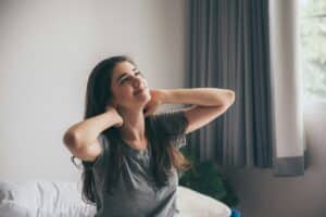 Woman holding a warm coffee cup outdoors, wearing a winter hat and sweate,r with snowy scenery behind her