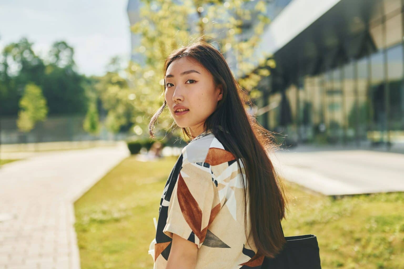 An Asian American woman looking back thoughtfully, expressing awareness, curiosity, and quiet confidence.