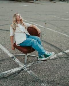 A woman sitting on an office chair in a playground, looking up, symbolizes imbalance, pressure, and seeking clarity.