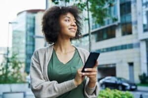 An African American woman holding a phone with a slight smile, reflecting awareness, connection, and composed presence.