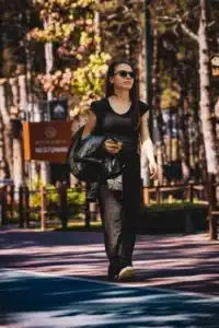 A woman in a black t-shirt and sunglasses walking on a path.