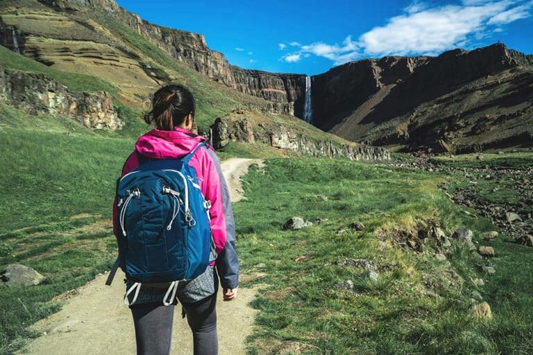 A woman traveler trekking through Iceland’s landscape during summer.