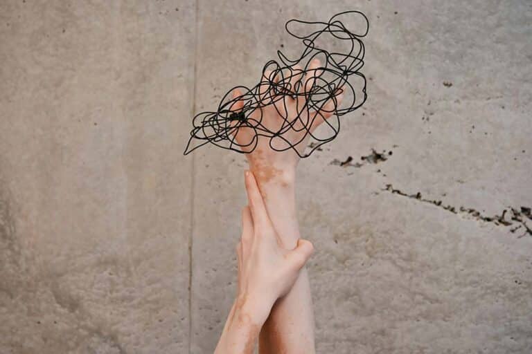 Two hands reaching up toward a wall.