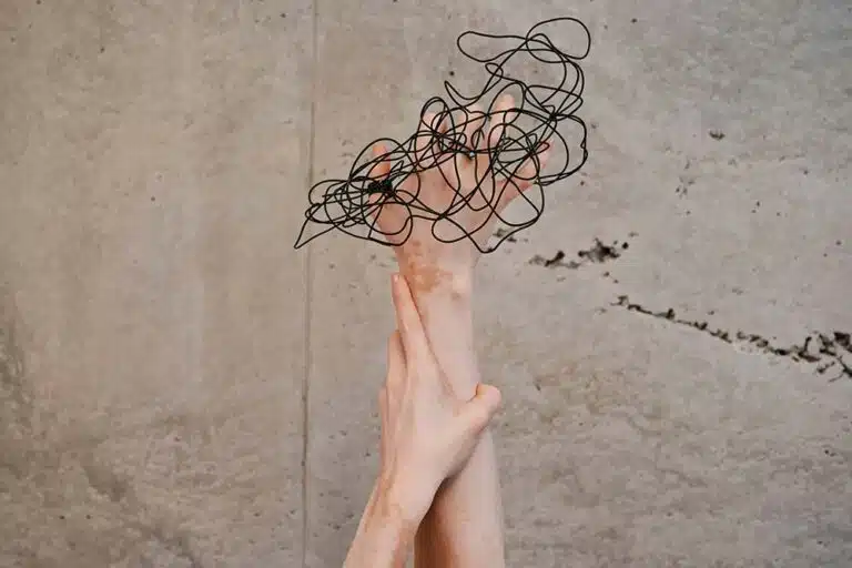 Two hands reaching up toward a wall.