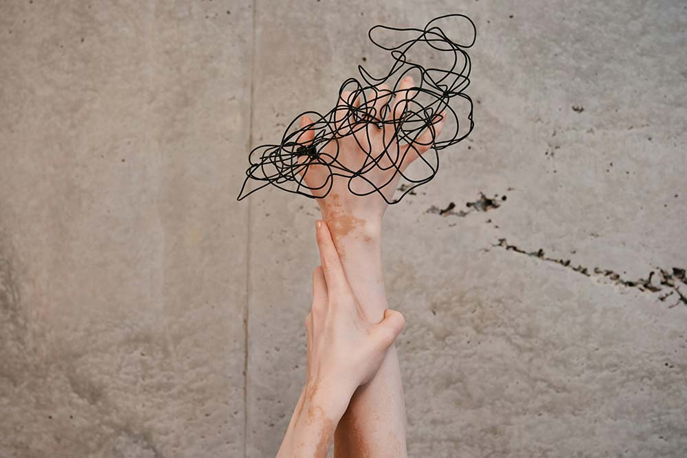 Two hands reaching up toward a wall.