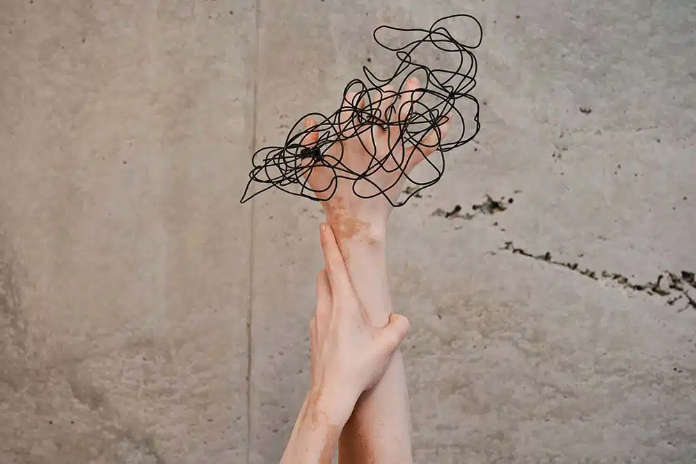 Two hands reaching up toward a wall.